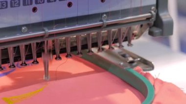 Kırmızı kumaş üzerinde sarı Nike logosu yapan nakış makinesi