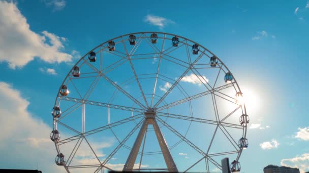 Silhueta de roda gigante girando contra o céu azul com nuvens: brilho da lente solar — Vídeo de Stock