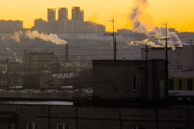 TV antenli eski binaların çatıları ve gün doğumuna karşı beyaz dumanlar.