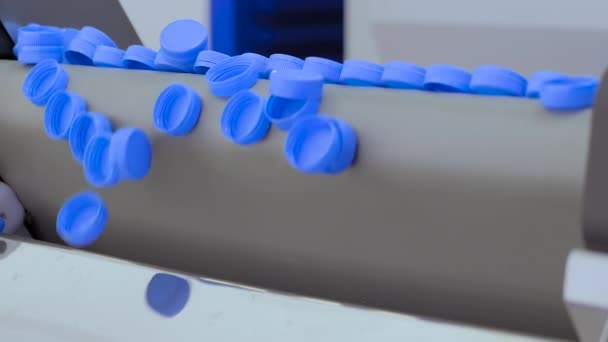 Veel blauwe plastic flessendoppen vallen van transportband - slow motion — Stockvideo