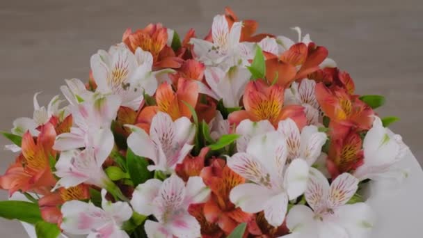 Μπουκέτο με πορτοκαλί και λευκά λουλούδια αλστρομέρια στην περιστρεφόμενη επιφάνεια: κοντά — Αρχείο Βίντεο