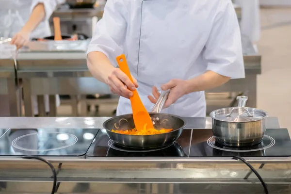 Chef hands cooking vegetables - sliced bell pepper, onion in frying pan