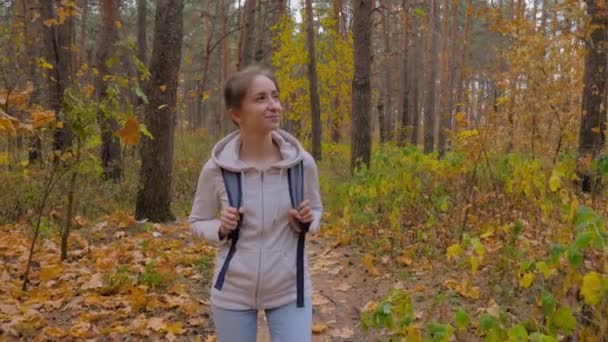 Elülső kilátás fiatal nő hátizsák séta őszi parkban - steadicam lövés — Stock videók