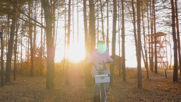 Front view: kvinna ridning cykel i höst stadspark i solnedgången - slow motion — Stockvideo