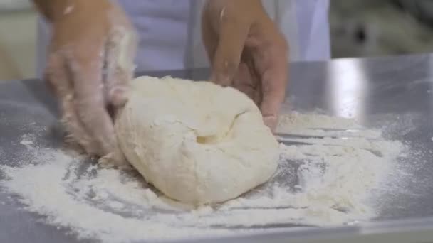 Zamknij: ręce piekarza ugniatanie świeżego ciasta na stole w piekarni — Wideo stockowe
