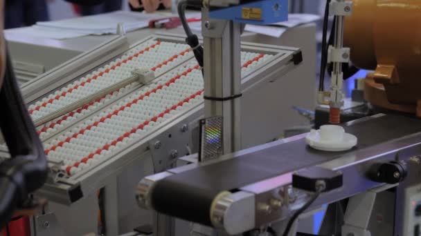 Choisissez et placez le manipulateur robotique de bras déplaçant le détail en plastique sur la bande transporteuse — Video