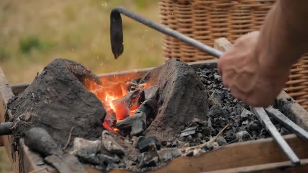 Kovář topení kovový kus ve venkovní kovárně na medival festivalu - zblízka — Stock video