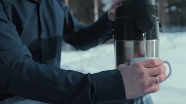 ahşap genç bir çift. adam bir termosa çay dökülen.