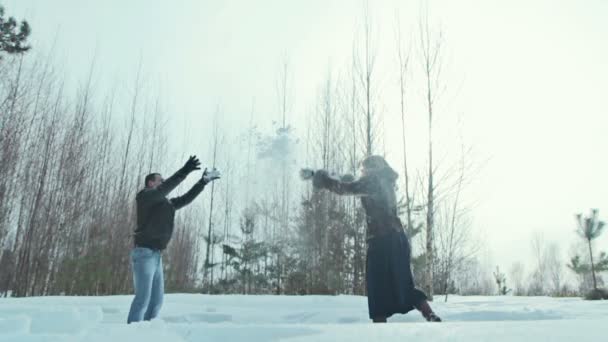 Pareja joven jugando al aire libre en la nieve . — Vídeos de Stock