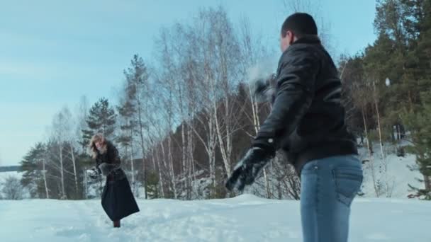 冬の森、スローモーションで雪で雪だるまを持っているカップルの戦い — ストック動画