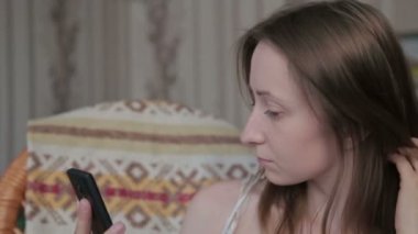 İle akıllı telefon oturan genç güzel kadın.