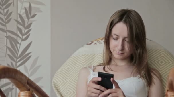Молода красива жінка сидить зі смартфоном . — стокове відео