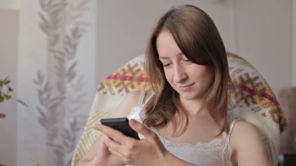 Mladá krásná žena, sedící s Kobaltová modř telefon. — Stock video