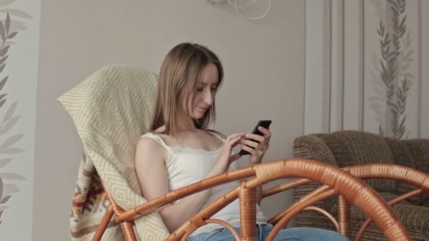 Junge schöne Frau sitzt mit Smartphone. — Stockvideo