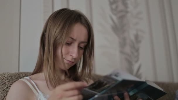 Jeune femme lisant un livre sur le canapé — Video