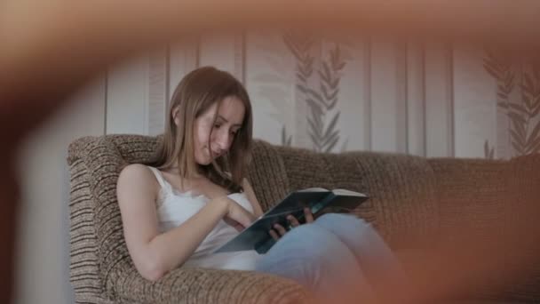 Mladá žena čtení knihy na gauči — Stock video