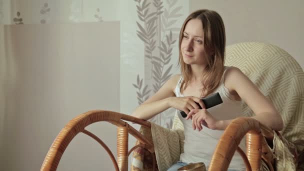 Girl on armchair, rocker with remote control — Stock Video