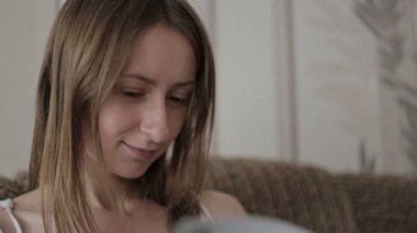 Kanepede kitap okuyan genç bir kadın.