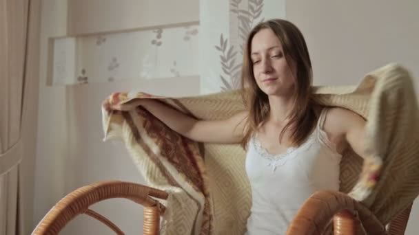 Young woman covered with blanket holding remote control and watching tv at home — Stock Video