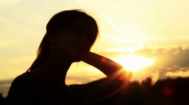 Bir kadının saçını dokunmadan bir günbatımı üzerinde bir siluet