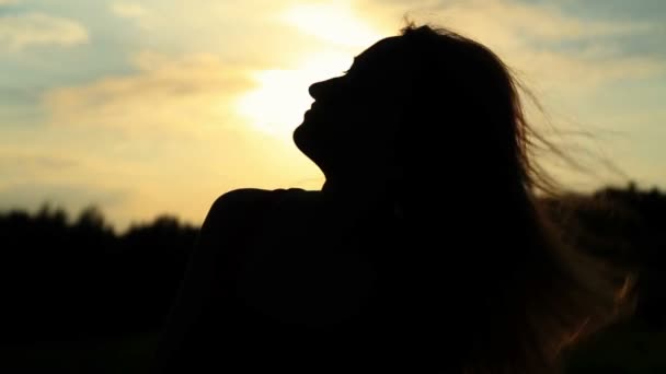 Una silueta de una mujer en una puesta de sol tocándose el pelo — Vídeos de Stock