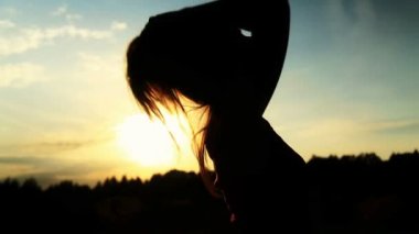 Bir kadının saçını dokunmadan bir günbatımı üzerinde bir siluet