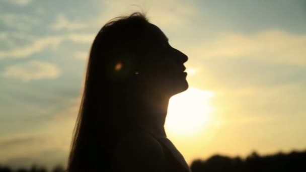 Una silueta de una mujer en una puesta de sol tocándose el pelo — Vídeo de stock