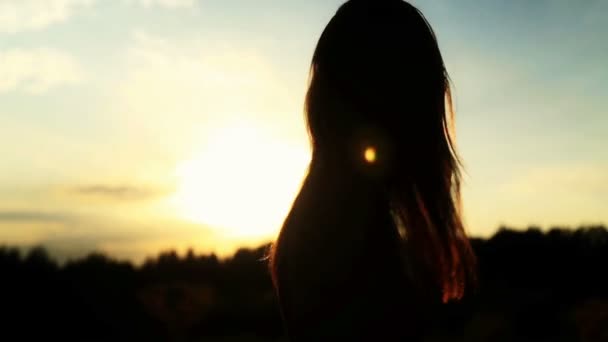 Uma silhueta de uma mulher ao pôr-do-sol vira a cabeça e dança — Vídeo de Stock