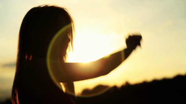 Silhueta da mulher dançando durante o belo pôr do sol. Luz natural e escuridão . — Vídeo de Stock
