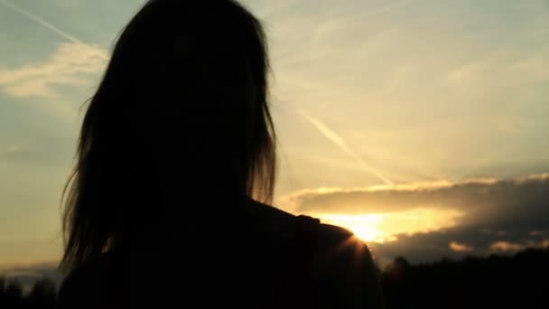 Une silhouette de femme sur un rayon de soleil couchant ses cheveux — Video