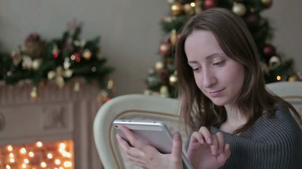 Mujer feliz mirando en la tableta PC en frente del árbol de Navidad — Vídeo de stock