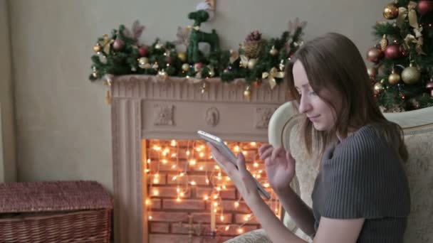 Mulher feliz olhando no PC tablet na frente da árvore de Natal — Vídeo de Stock