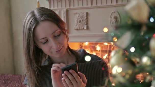 Mujer usando su teléfono móvil en Navidad en casa en la sala de estar — Vídeo de stock