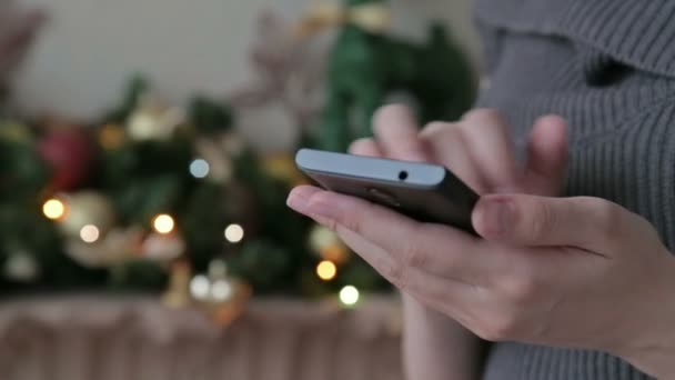 Femme utilisant son téléphone portable à Noël à la maison dans le salon 