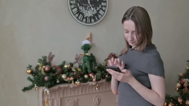 Frau benutzt ihr Handy zu Weihnachten zu Hause im Wohnzimmer — Stockvideo