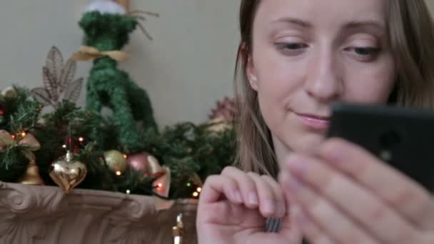 Frau benutzt ihr Handy zu Weihnachten zu Hause im Wohnzimmer — Stockvideo