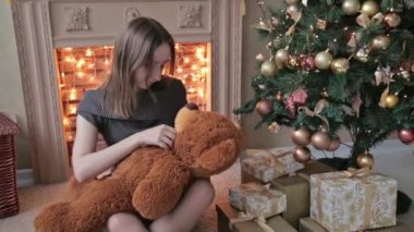 Zemin ve hugs, üzerinde oturan genç kadın atmak, büyük bir oyuncak ayı içinde Noel süsleri dokunmatik