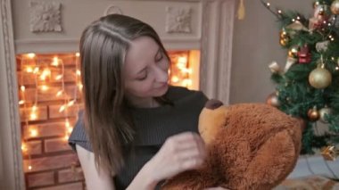 Zemin ve hugs, üzerinde oturan genç kadın atmak, büyük bir oyuncak ayı içinde Noel süsleri dokunmatik
