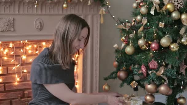 Young woman with gifts in front of Christmas tree — Stock Video