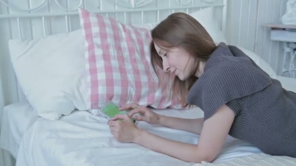 Femme heureuse regardant dans la tablette PC sur le lit — Video