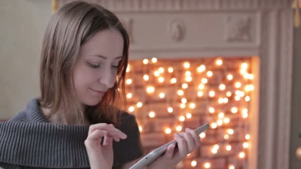 Gelukkige vrouw op zoek in tablet pc voor kerstboom — Stockvideo