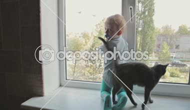 Kara kedi evde pencere oturmak ile küçük çocuk