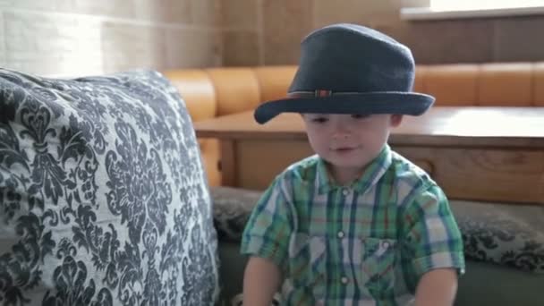 Chłopiec z zabawny kapelusz rzucać piłkę w domu — Wideo stockowe