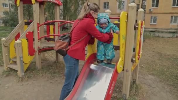 Kleiner Junge rutscht mit seiner Mutter auf Spielplatz — Stockvideo