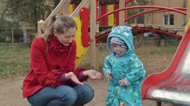 Petit garçon jouer avec sa mère avec une voiture jouet dans l'aire de jeux — Video