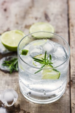 Cocktail with ice and lime slice on wooden background