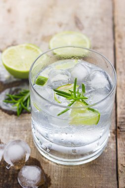 Cocktail with ice and lime slice on wooden background