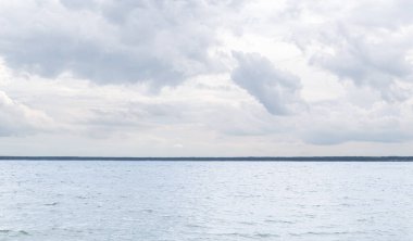 Göl manzarası. Dalgalı bir gölün üzerinde güzel beyaz kümülüs bulutları. Ufuk. Manzara. Yaz zamanı. Yatay fotoğraf.