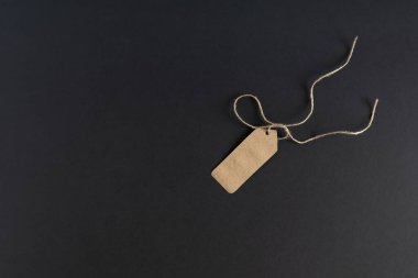 Karanlık bir arka planda, boş bir alışveriş etiketi, ipli el işi kağıdından yapılmış bir etiket. Model, reklam broşürü. Mesajın için yer aç. Yatay fotoğraf. 