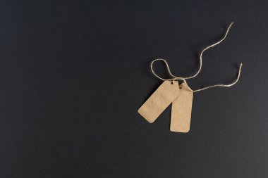 Karanlık bir arka planda, iki boş ticari etiket, kraft kağıdından ipli fiyat etiketleri. Model, reklam broşürü. Mesajın için yer aç. Yatay fotoğraf. 